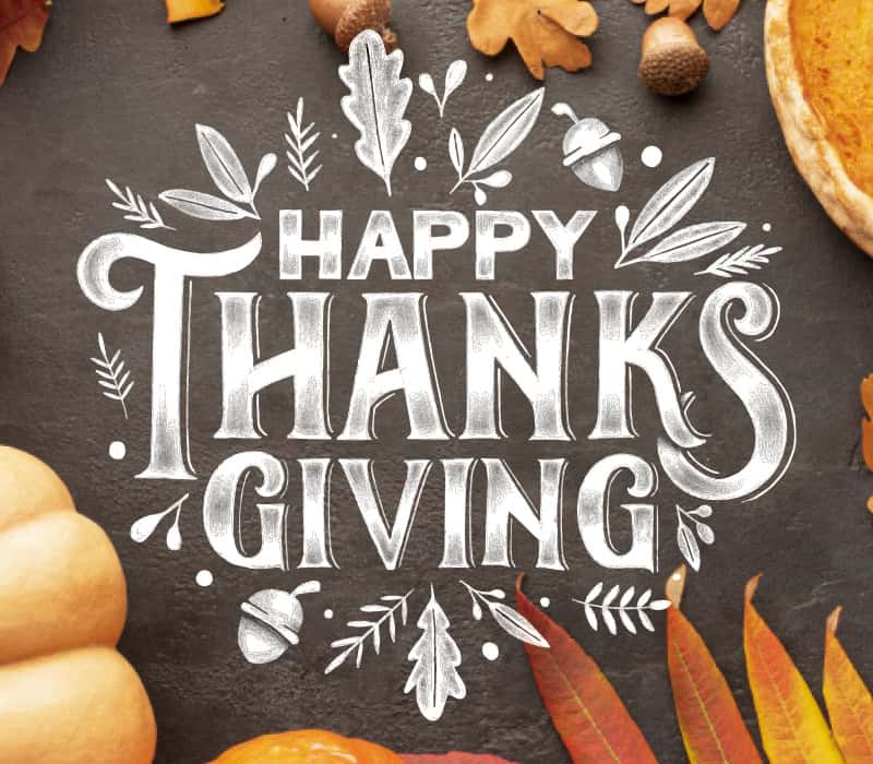 Chalk-style “Happy Thanksgiving” text on a dark background, surrounded by autumn leaves, acorns, a pumpkin, and part of a pumpkin pie.